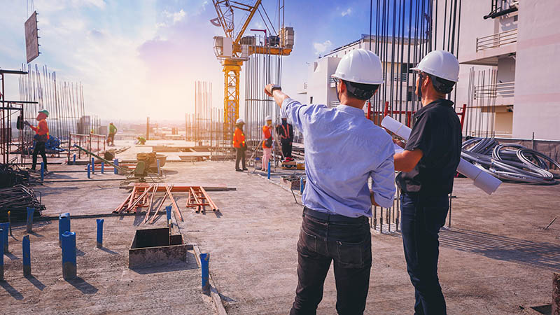 Smart civil architect engineer inspecting and working outdoors structure building site with blueprints. engineering and architecture concept.